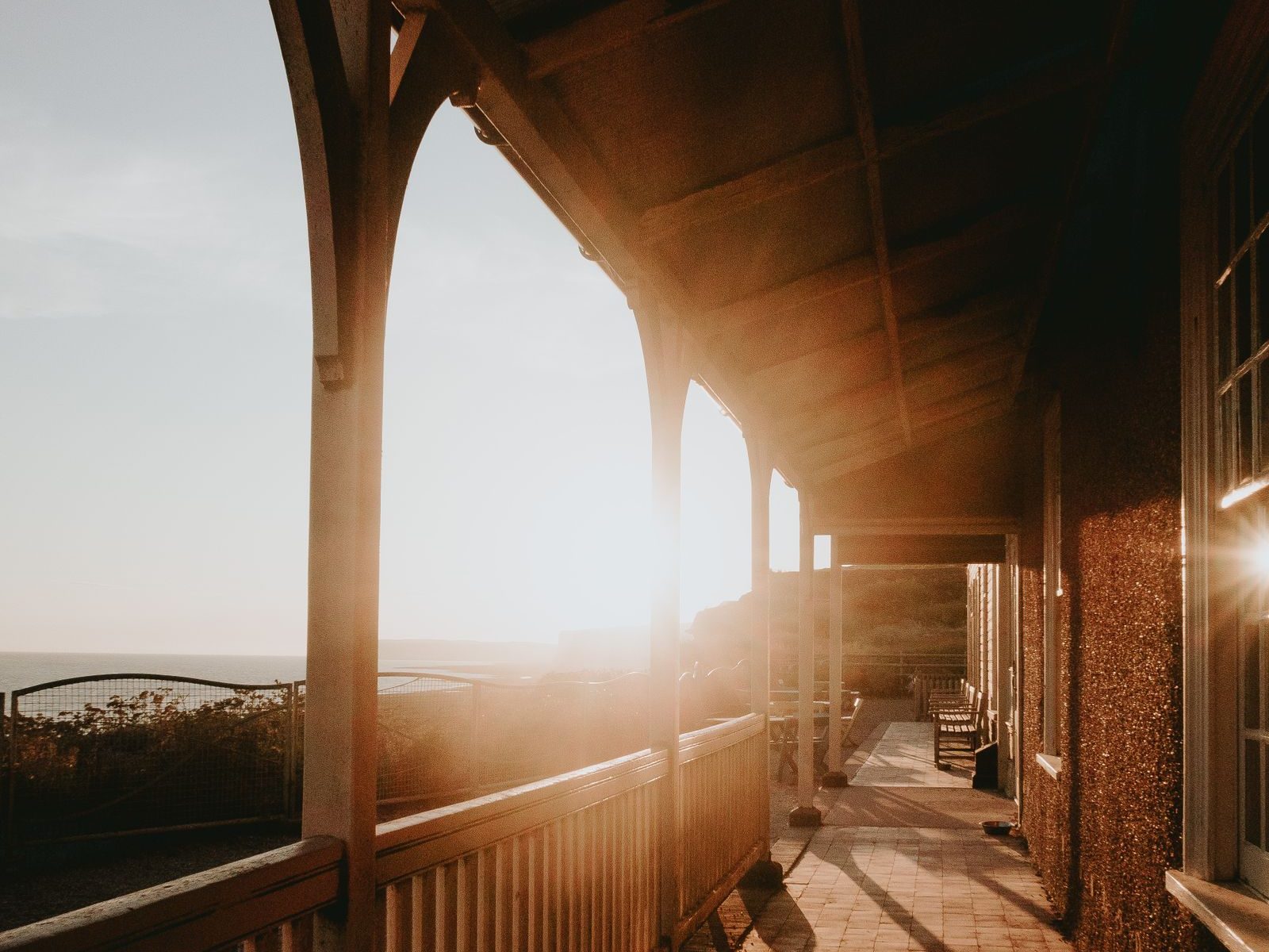 Morning sun along the timber veranda of an old guesthouse, with a valley view beyond the railing